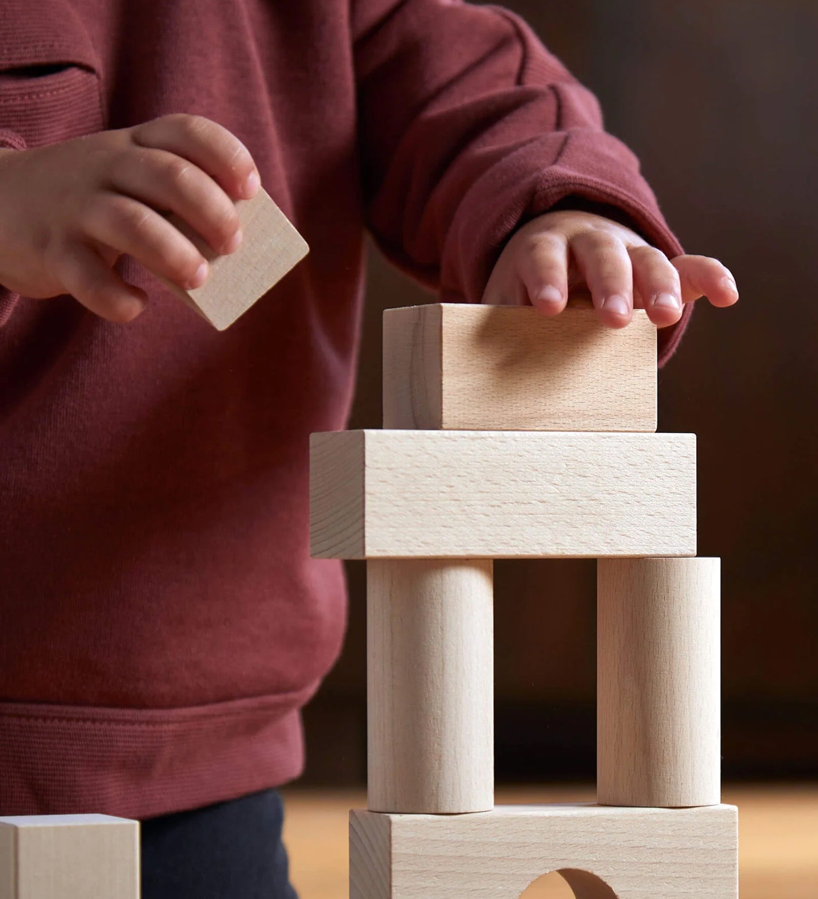 A child carefully placing the Haba Large Building Blocks on top of each other