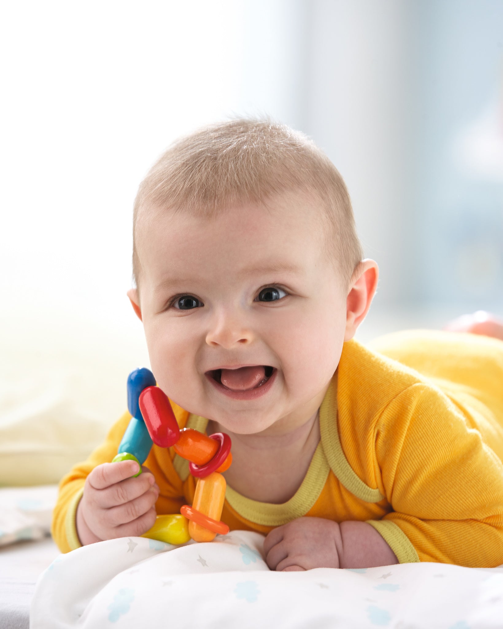 A baby happily chewing on the HABA Dilly Dally clutching and teething ring beads