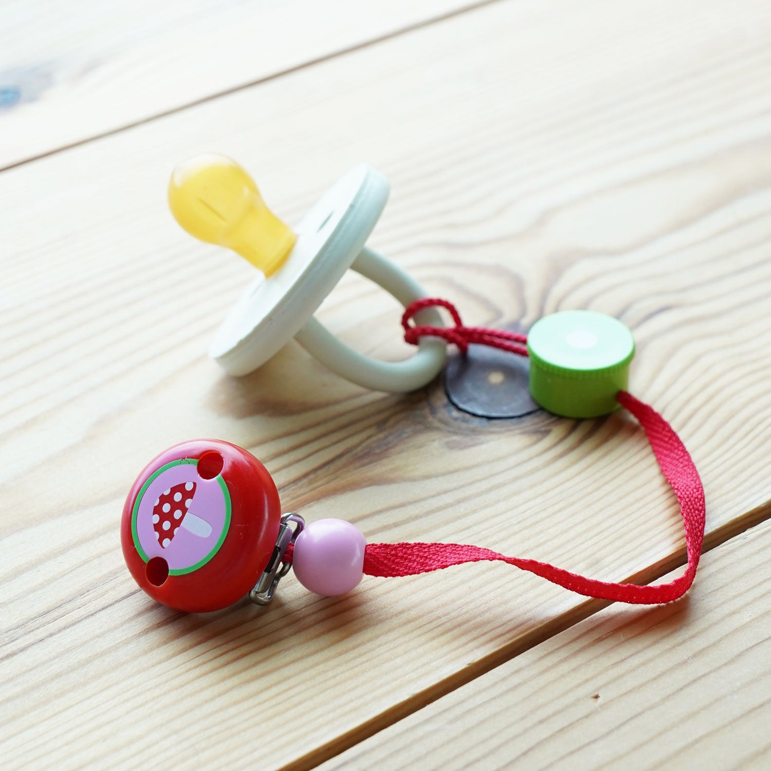 Heimess Baby Teether Chain - Toadstool pictured attached to a Heimess pacifier