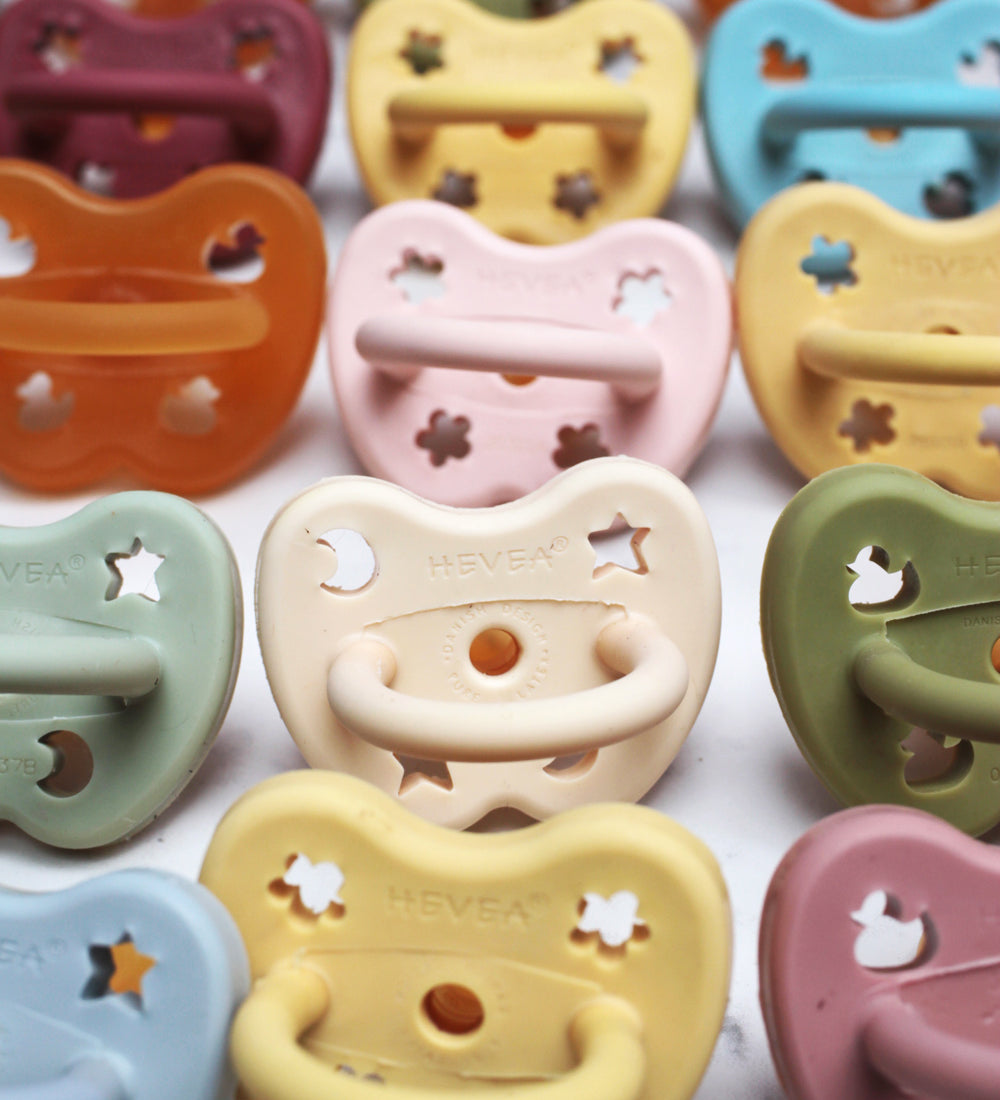 Close up of the Hevea natural rubber baby pacifiers lined up on a white background