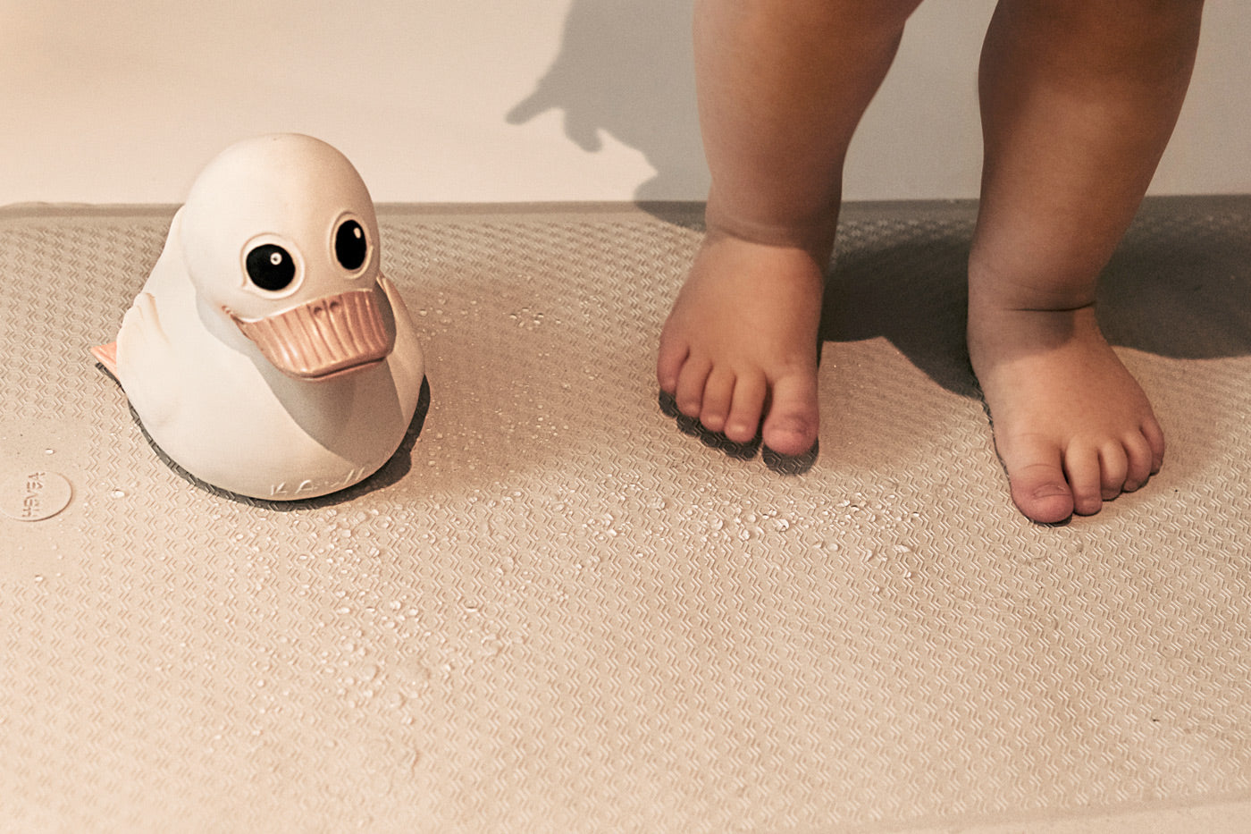 Close up of child's feet and rubber duck on a Hevea rubber bath mat