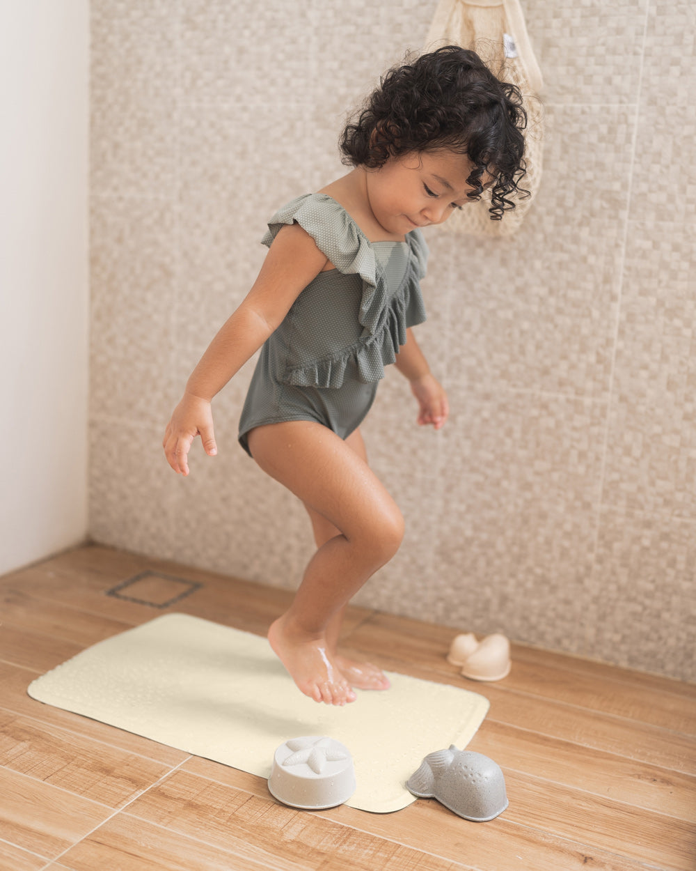 Child stood on the Hevea natural rubber bath mat in a beige shower