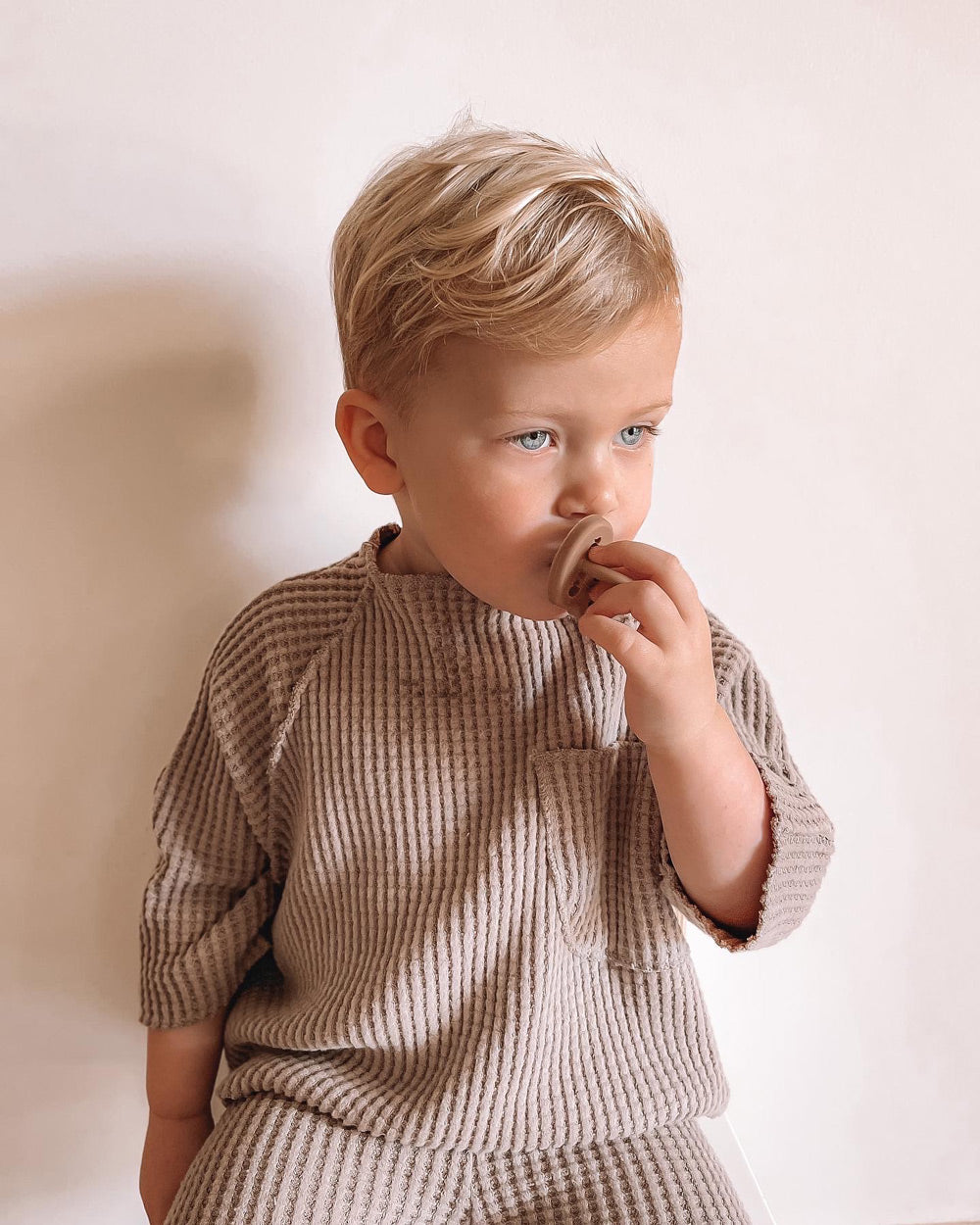 Close up of young boy touching the Hevea plastic-free dummy in his mouth