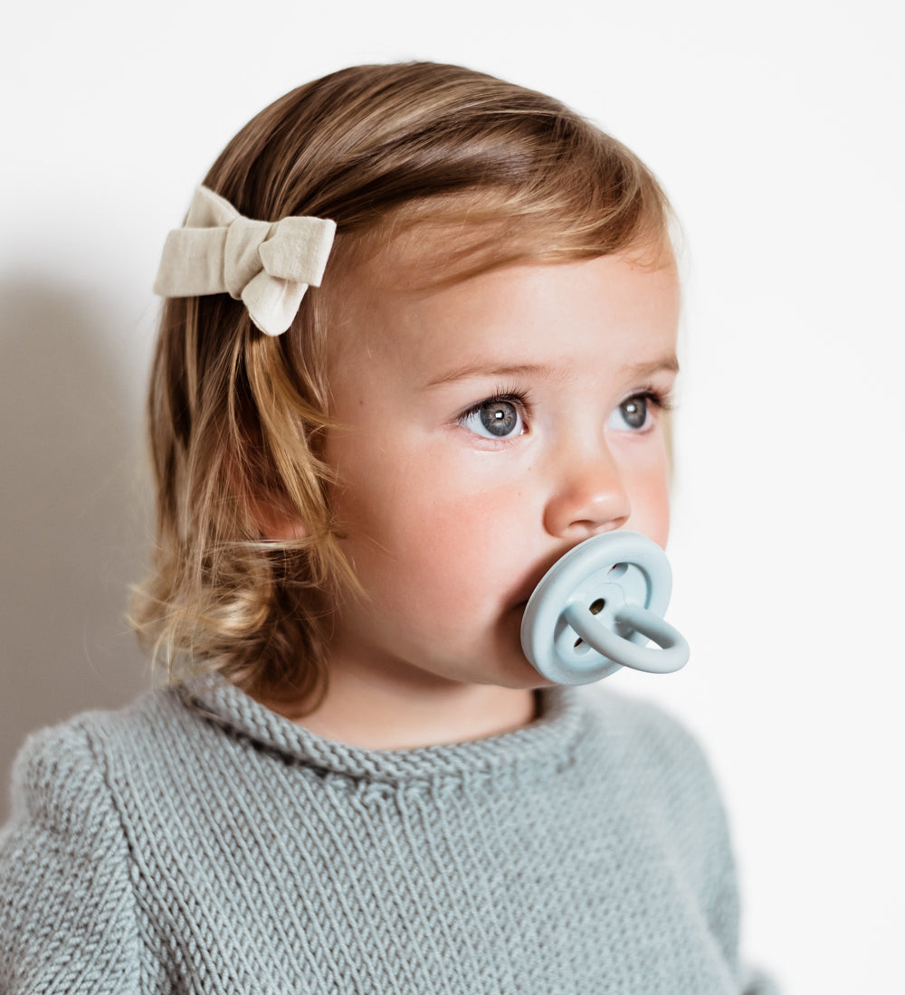 Close up of young child with a Hevea natural rubber pacifier in her mouth