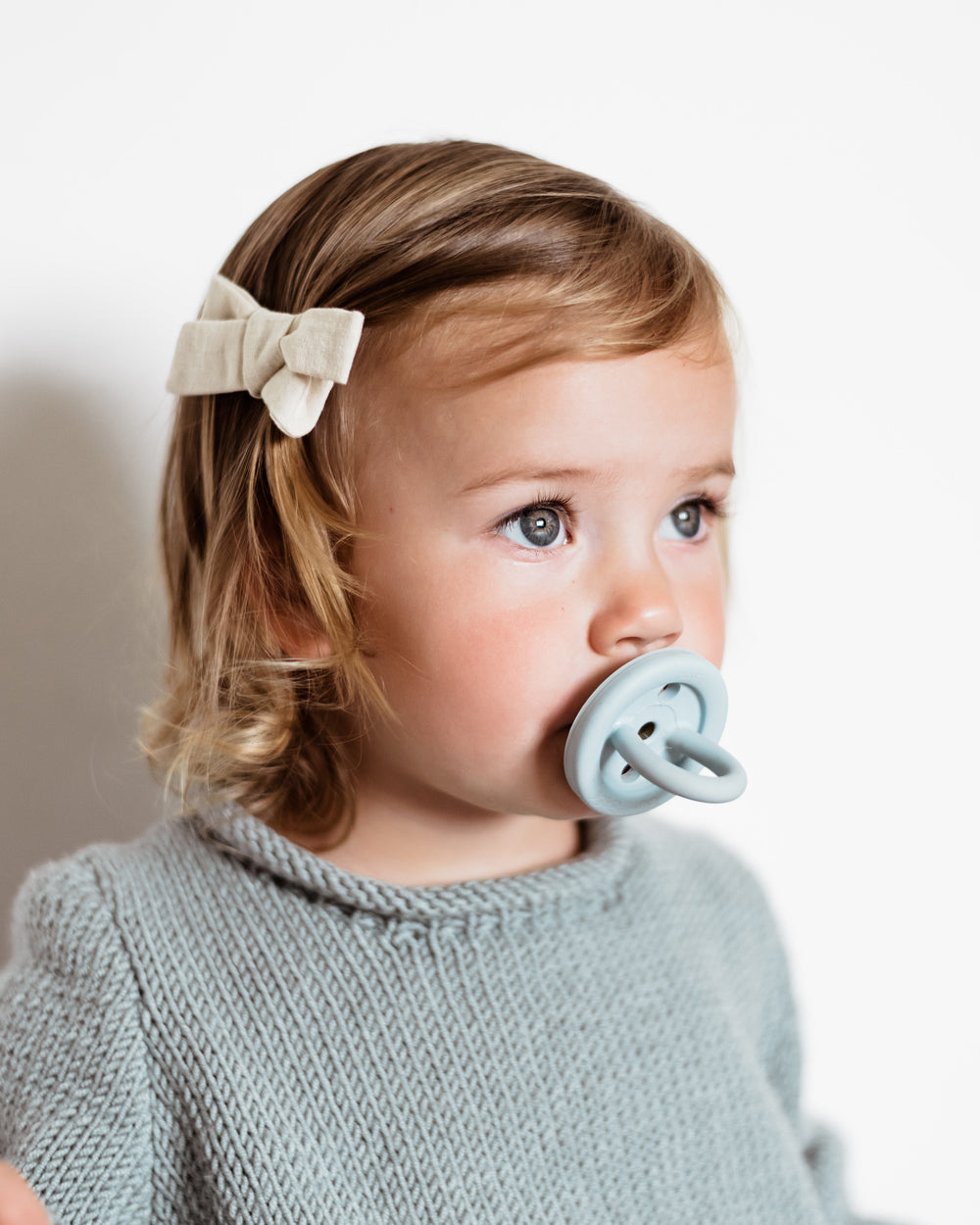 Close up of young child with a Hevea natural rubber pacifier in her mouth