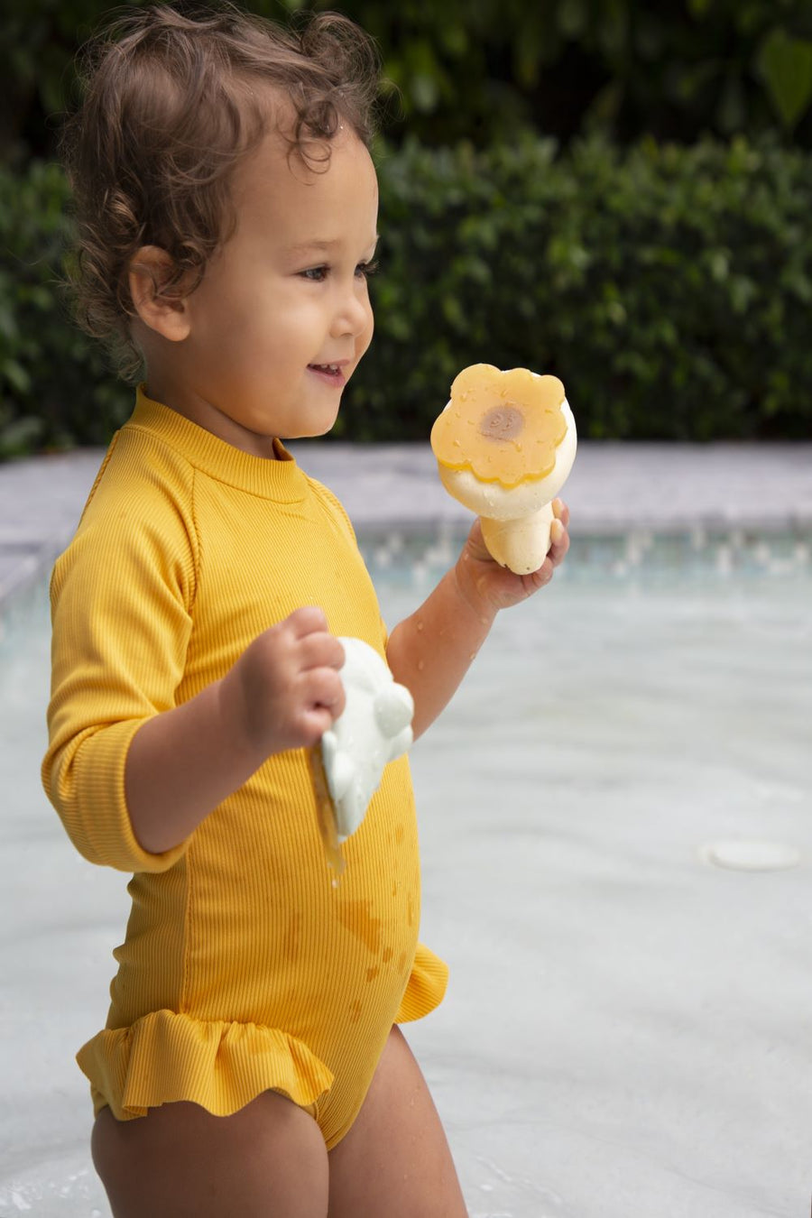 Hevea Upcycled rubber sand duck and sage frog toys being played in the pool by a small child