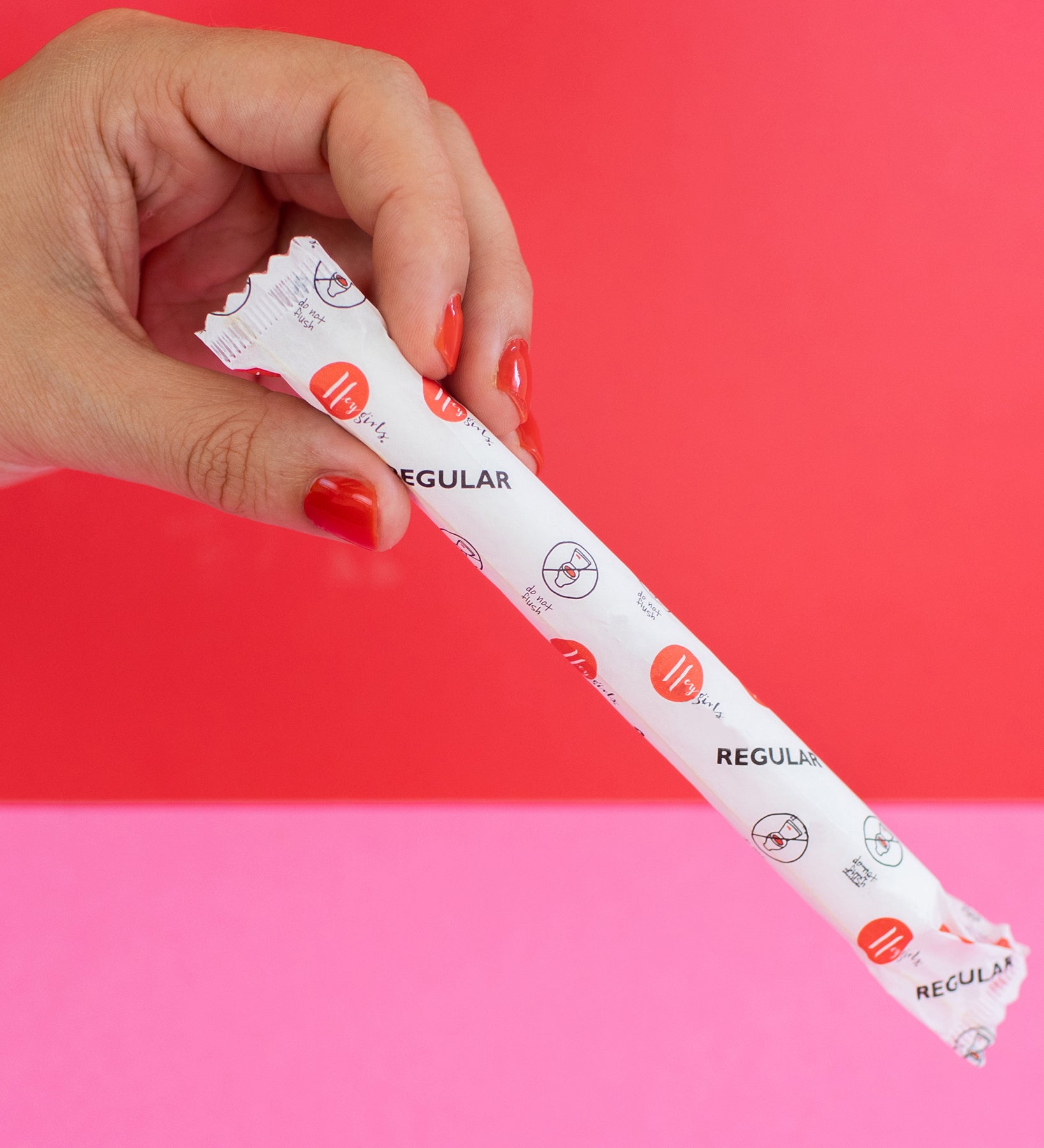 hey Girls Regular Absorbency Cardboard Applicator Tampons. Image shows a person with red nail varnish holding a tampon in its packet