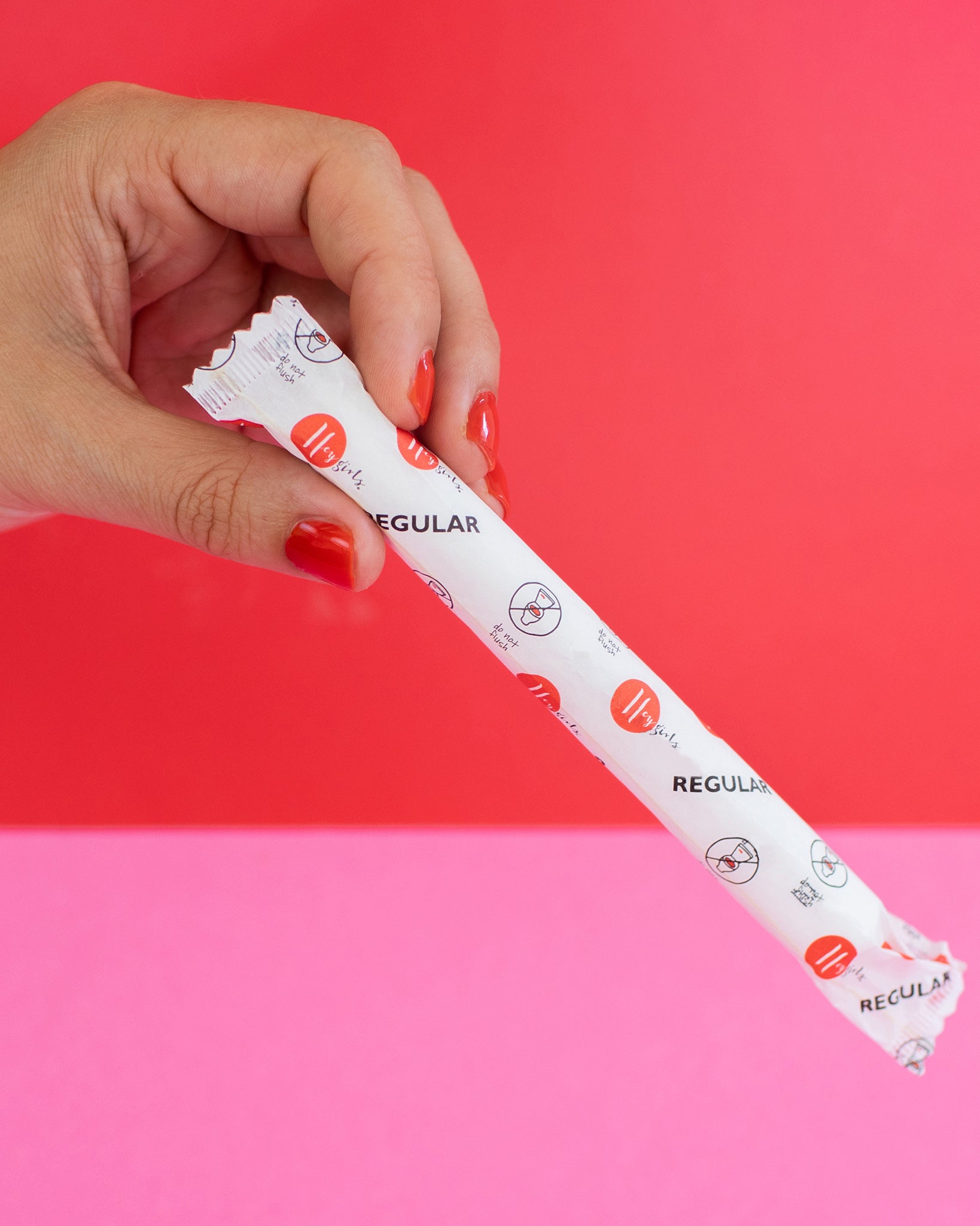 hey Girls Regular Absorbency Cardboard Applicator Tampons. Image shows a person with red nail varnish holding a tampon in its packet