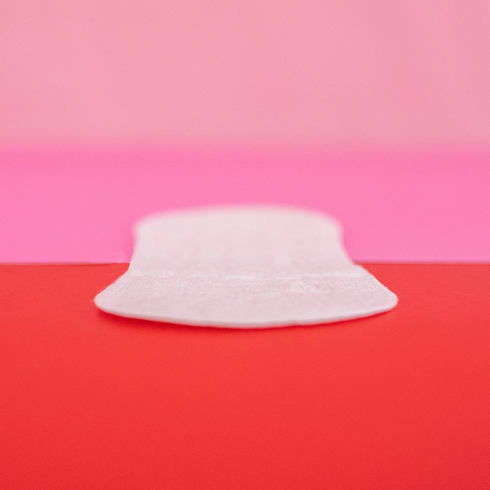 Hey Girls Natural Bamboo & Corn Fibre Disposable Panty Liners open in a persona hand on a red and pink background