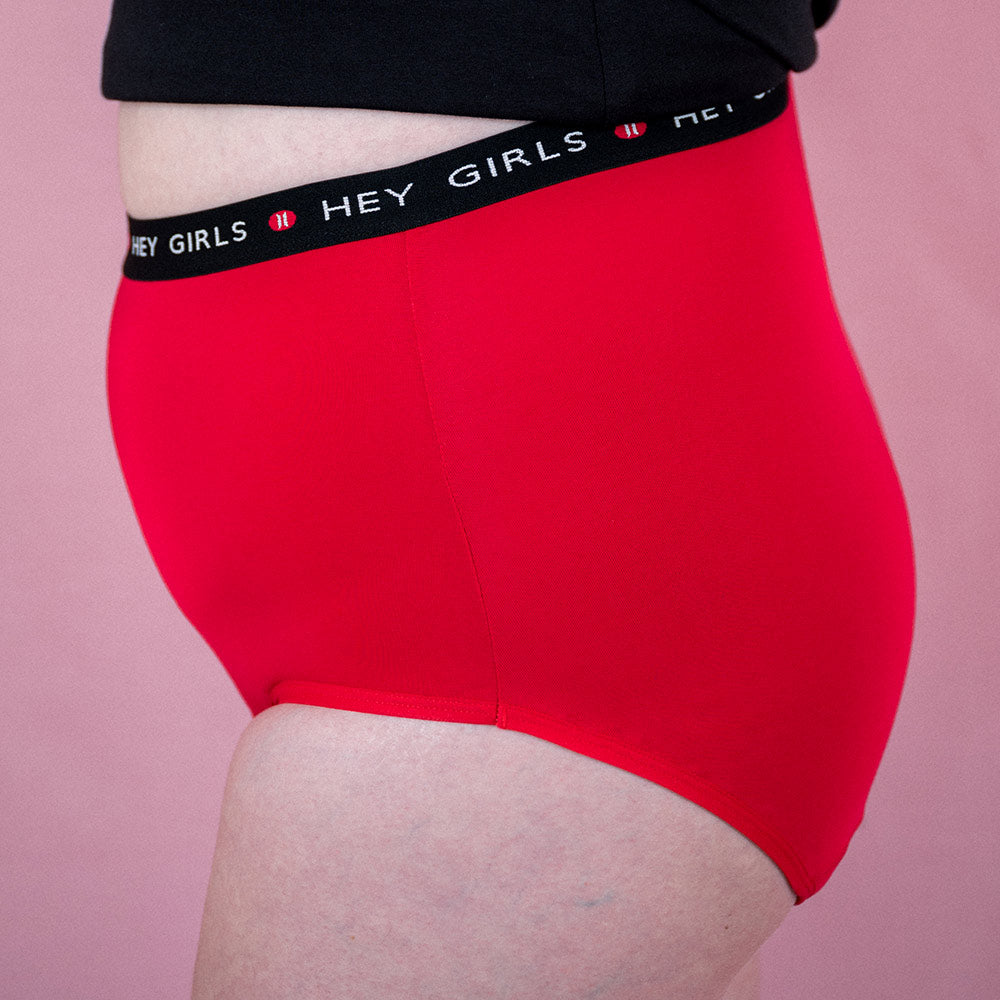 Hey Girls Super Soft Red Cherry Period Pants worn by a person with a black top on a pink background