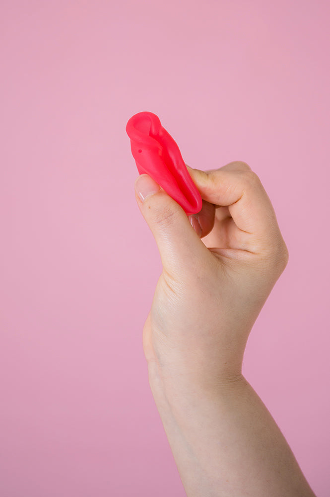 Hey Girls Large red Silicone Menstrual Cup held in someone's hand on a pink background