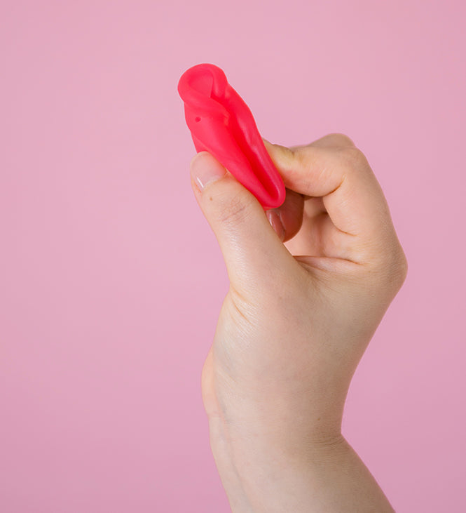 Hey Girls Large red Silicone Menstrual Cup held in someone's hand on a pink background