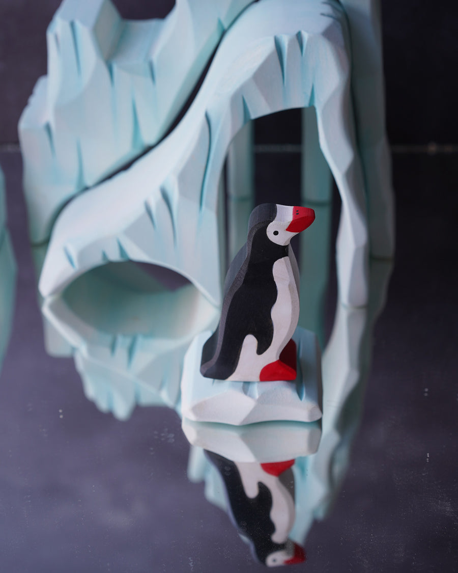 Holztiger Penguin figure stood in front of the Bumbu icy cliffs