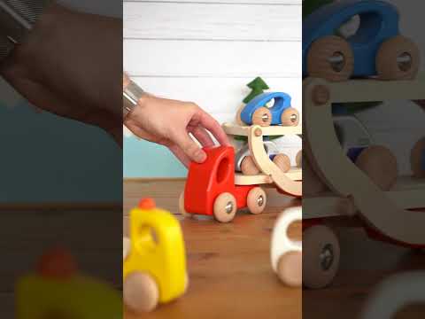 Close up of hand playing with the Bajo wooden transporter lorry toy on a wooden table