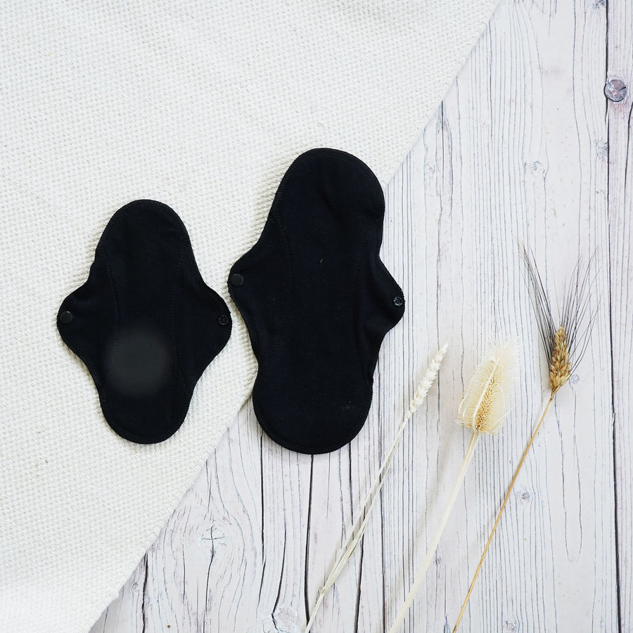 Imse Active Black Organic Cotton Panty Liners - 3 Pack pictured in a wooden surface 