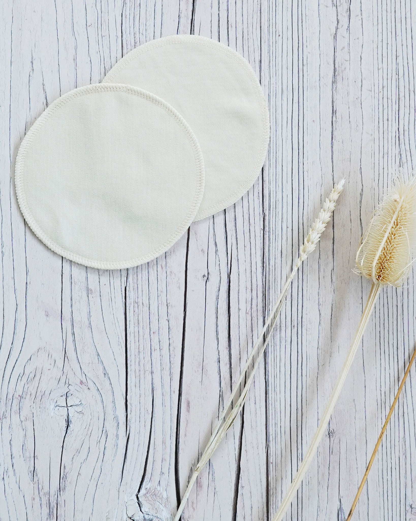 two Imse Vimse Merino Wool Breast Warmer Pads placed on a white coloured wooden background 