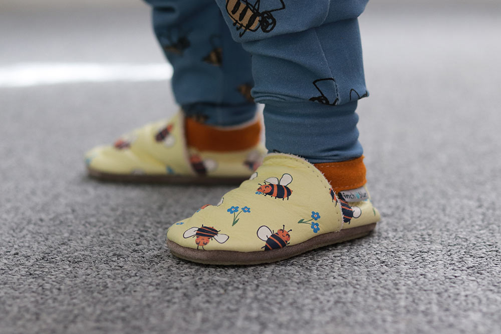 Inch Blue Leather Baby Shoes - bee happy yellow worn by a child wearing blue joggers with bee prints