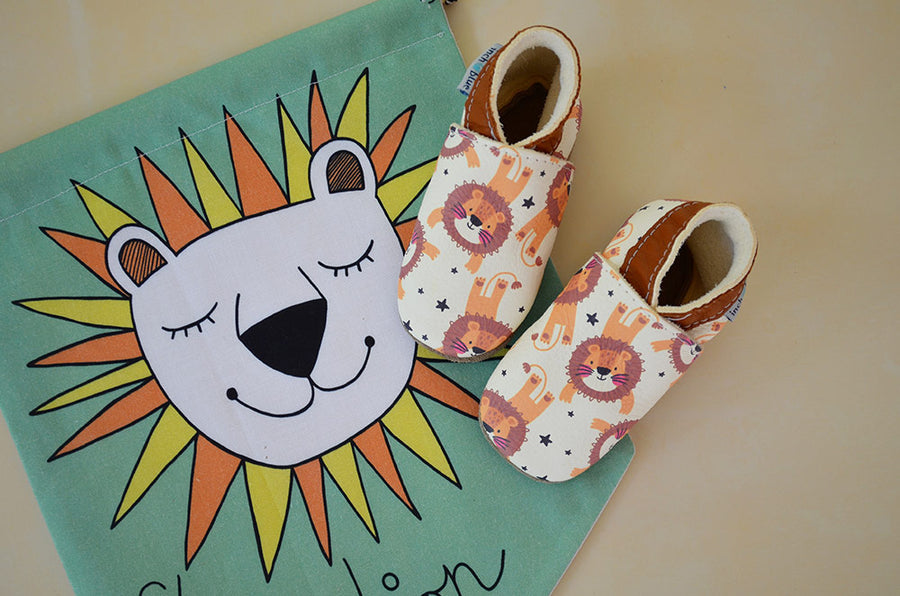 Inch Blue Leather Baby Shoes - Roar shoes on a cream floor with a lion printed bag underneath