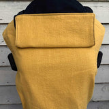 Integra ochre linen baby carrier in front of a white wooden fence