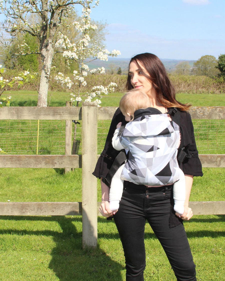 person babywearing on their front using an Integra baby carrier with a geometric design