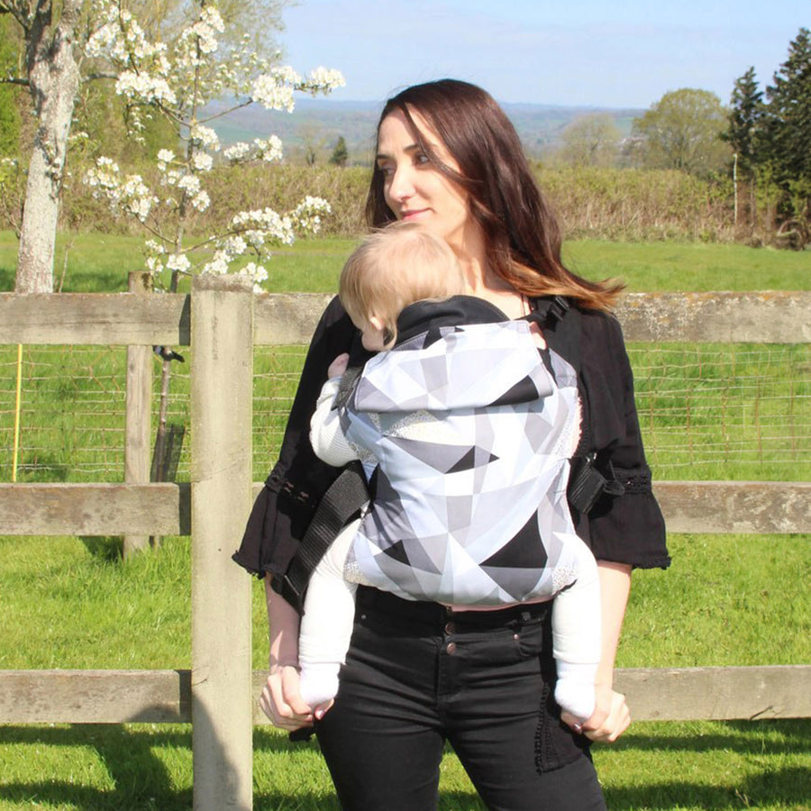 A woman wears an Integra Size 2 Regular Strap Baby Carrier outdoors.