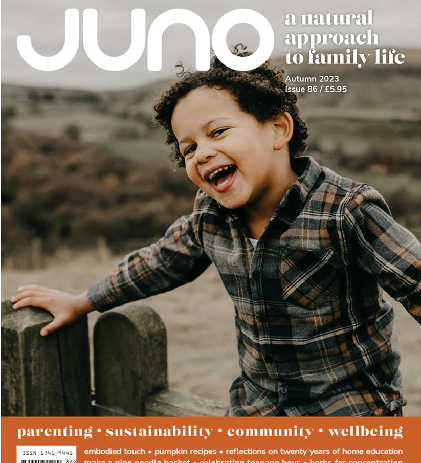 Juno Magazine cover pictures a young child on a beach with their toes in the sand and the water lapping at their feet.