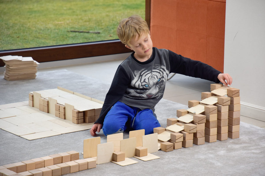 Young boy playing with a ball run made with wooden Just Blocks Smart Lines on a grey carpet