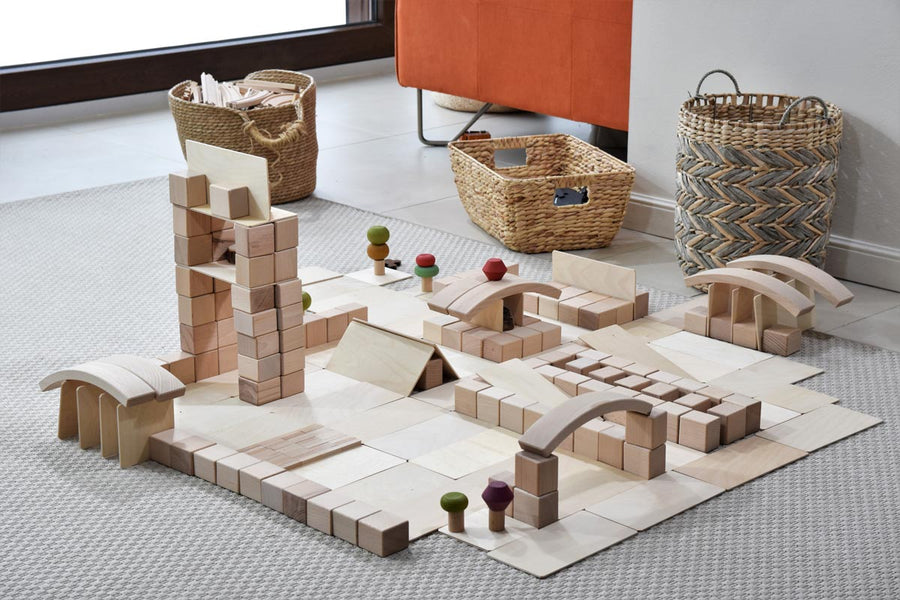 Just Blocks plastic-free wooden blocks stacked in a town scene on a grey carpet