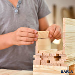 Close up of a child's hands stacking a pile of Kapla wooden building planks