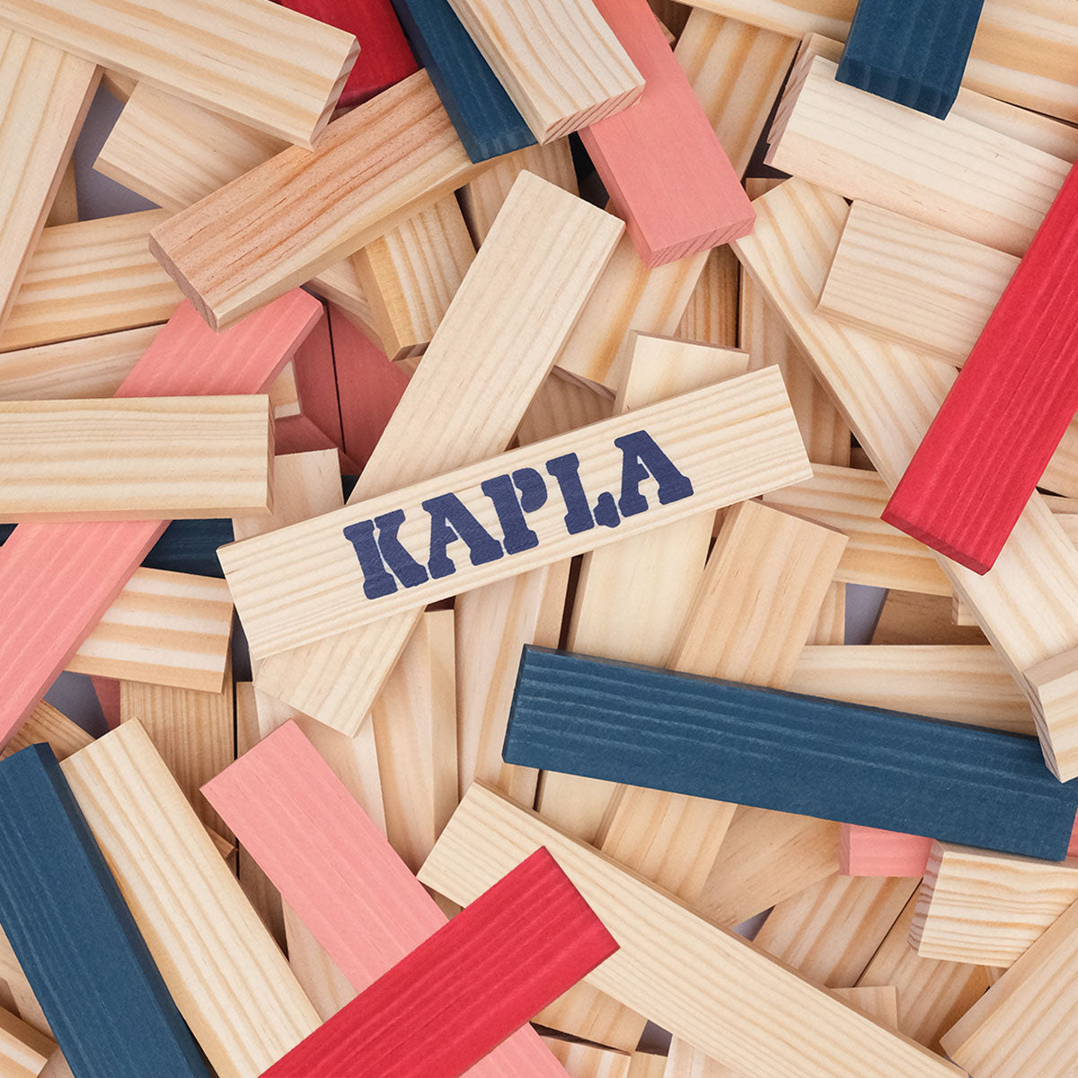 Close up of two girls making a tower with the Kapla Waldorf wooden toy blocks on a red and blue carpet