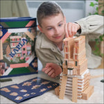 A child building a bunny shaped stack using the blocks from the KAPLA 200 Box wooden building planks in Spring colours. The box can be seen in the background