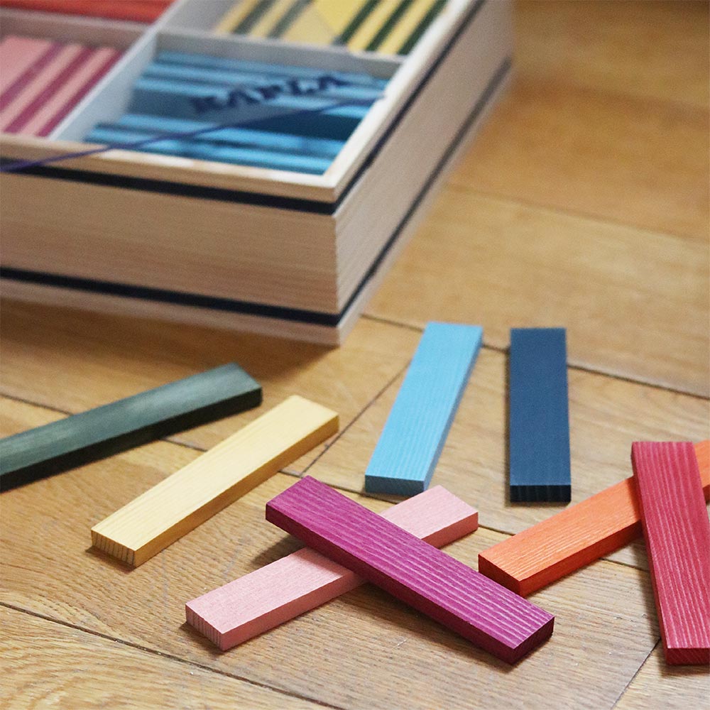 Kapla octocolour wooden blocks spread out on a wooden floor