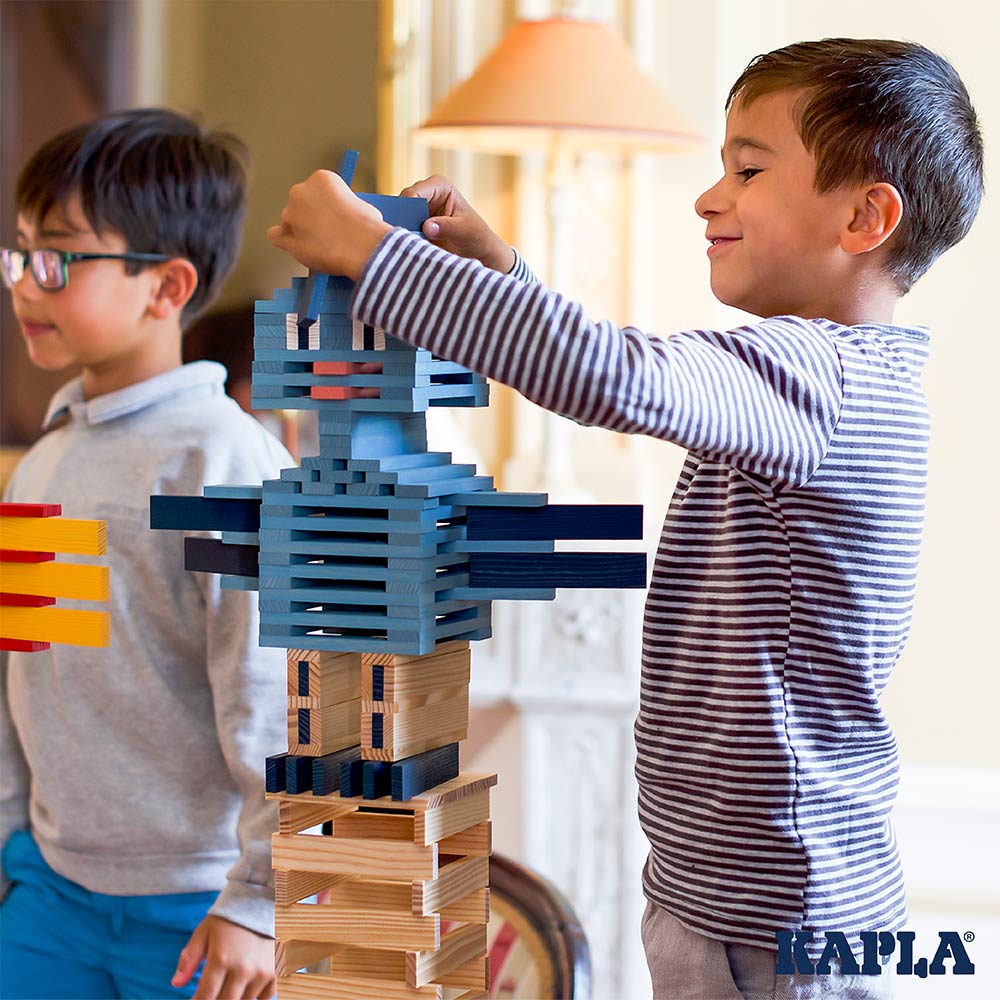 Child stacking up the Kapla eco-friendly wooden blocks to make a blue figure