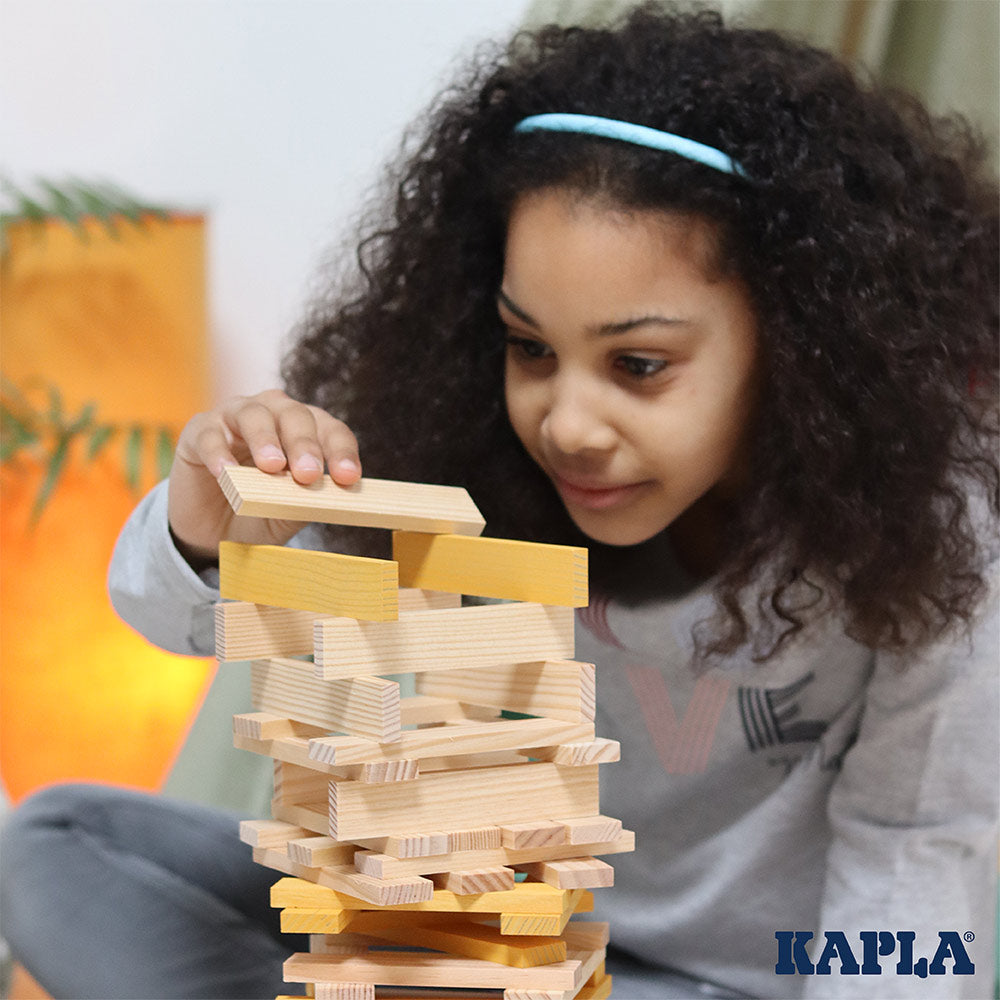 Close up of girl stacking the Kapla sustainable wooden building shapes into a tower