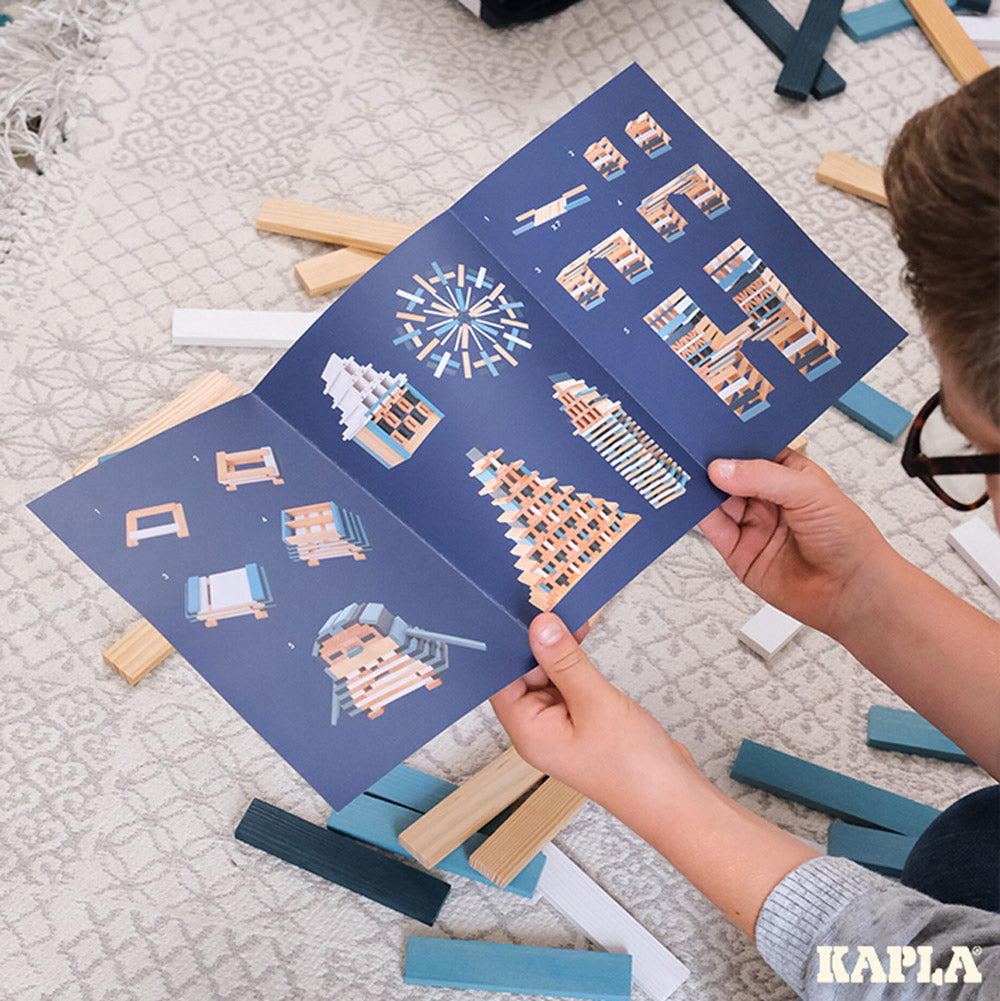 Close up of a child reading a book of Kapla building tutorials with the Kapla Winter set