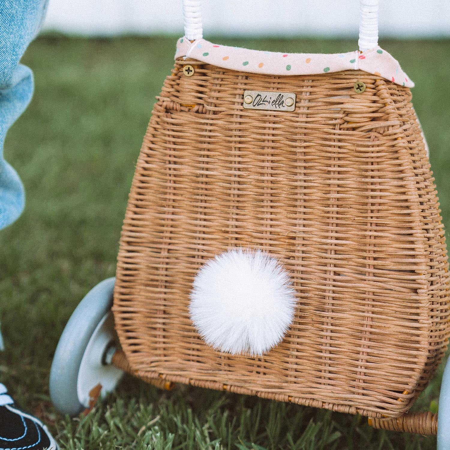 The back view of the Olli Ella Rattan Bunny Luggy with Lining – Gumdrop. A beautifully woven Luggy roll along basket with a light peach lining and gum drop detail