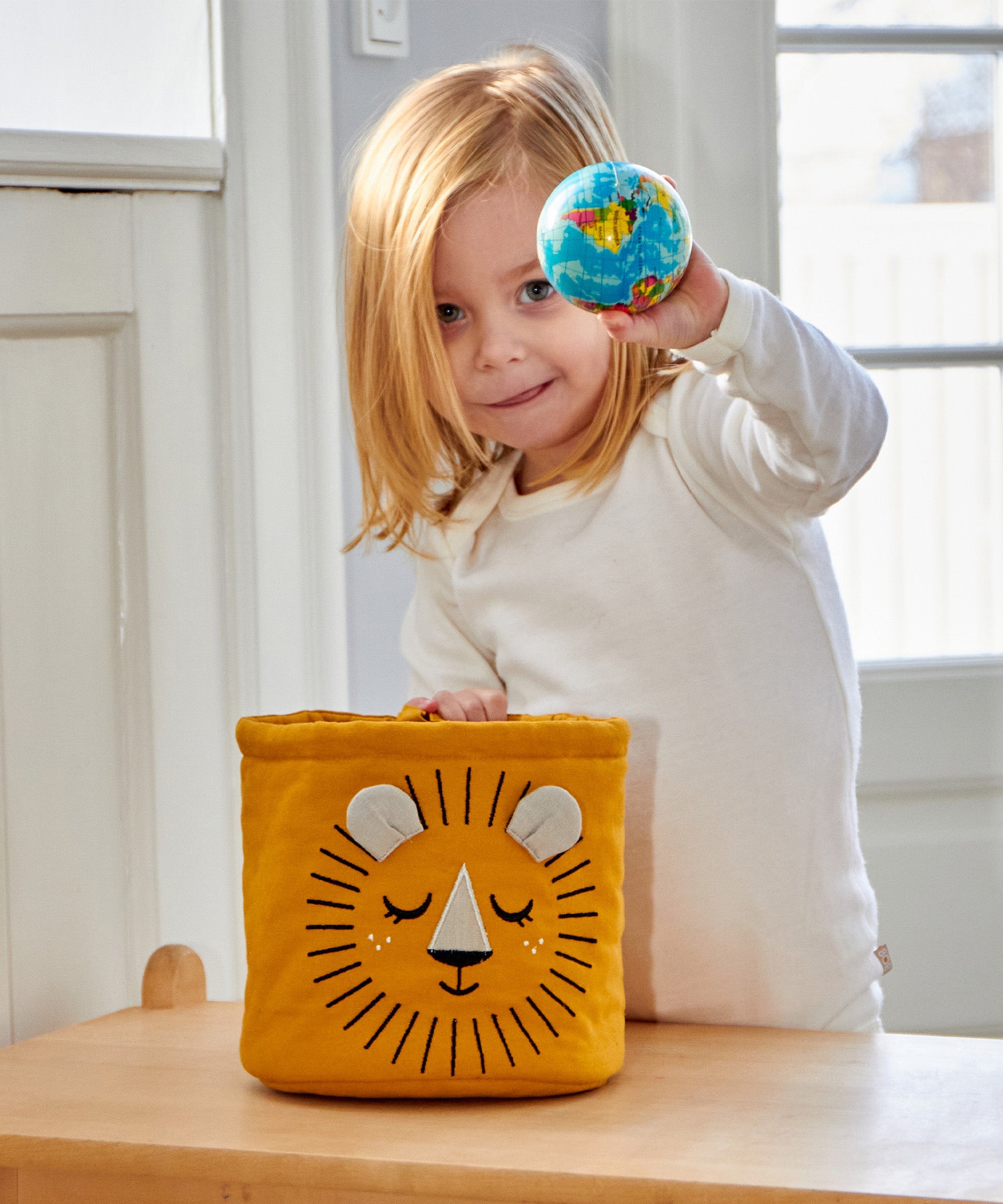 A child putting their hand into the The Roommate Mini Quilted Basket - Lion