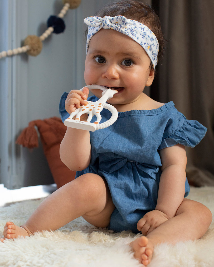 A baby sat on a light grey sofa