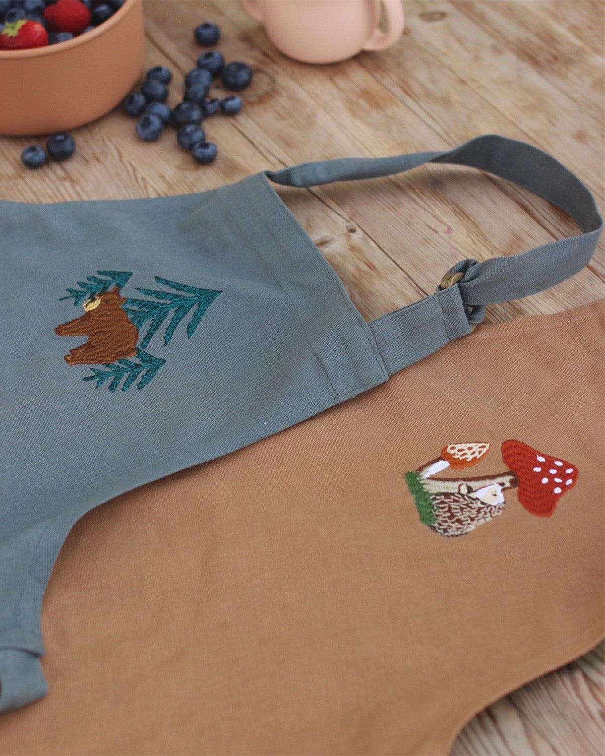 embroidered bear and tree pattern of the chest of the apron.