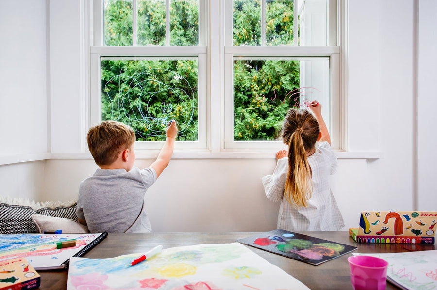 Top down view of children drawing with the Kitpas non-toxic crayons on some large white paper