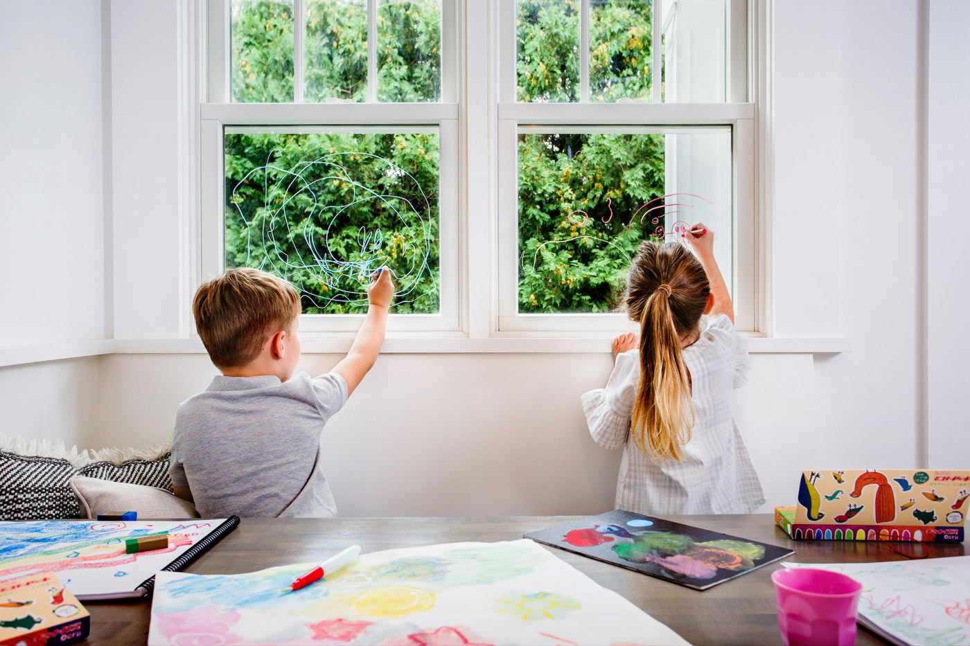 Top down view of children drawing with the Kitpas non-toxic crayons on some large white paper