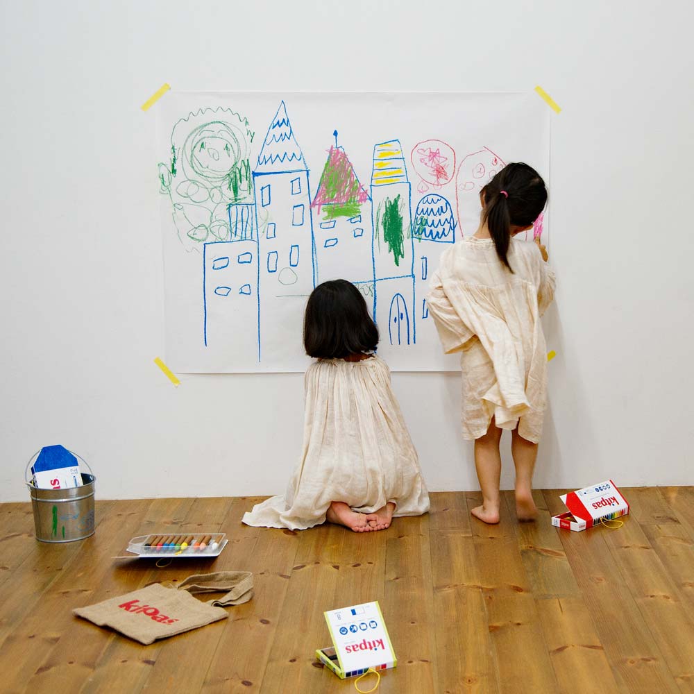 Two girls drawing with the Kitpas crayons on a large sheet of paper