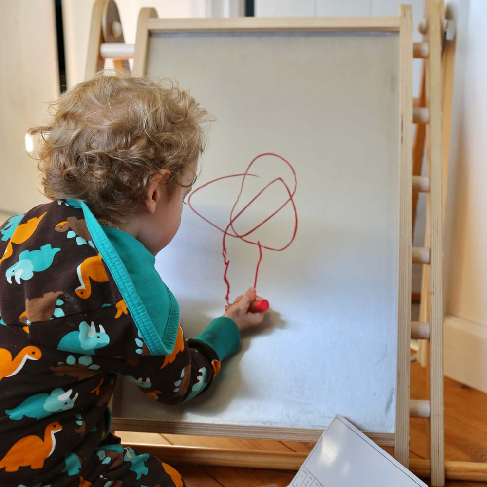 Close up of boy drawing with a Kitpas non-toxic bran wax crayon on a Triclimb Biri board