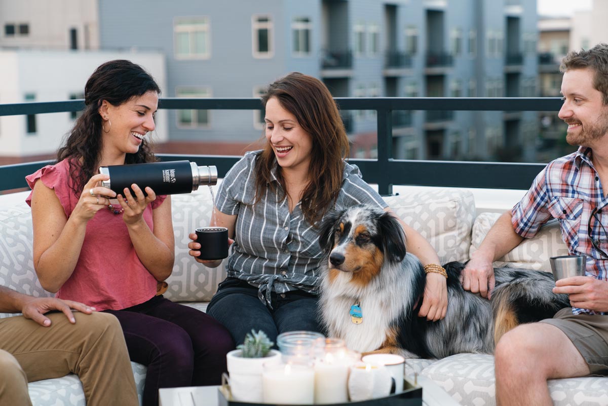 3 people and a dog sat on an outdoor sofa