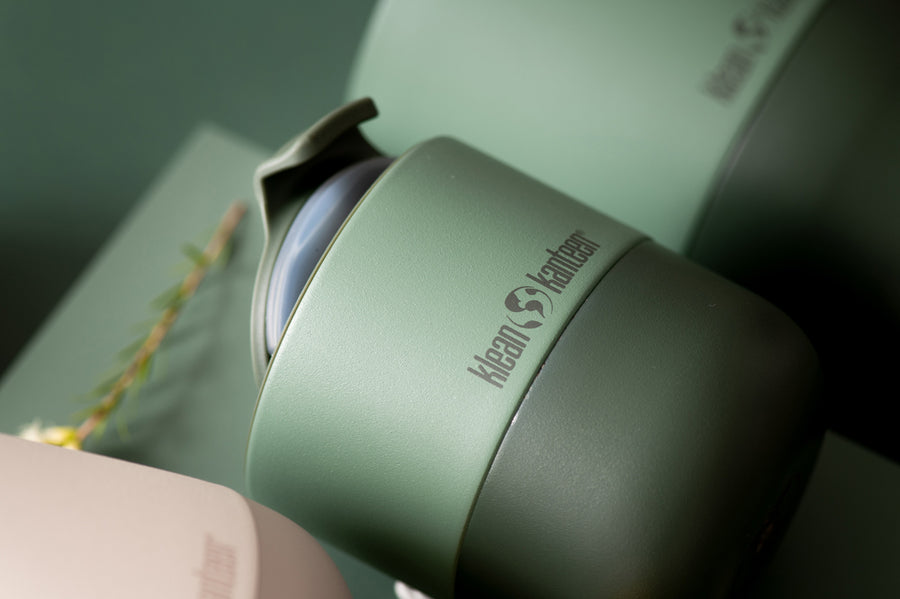 Close up of a dark green Klean Kanteen insulated lowball cup on a green background