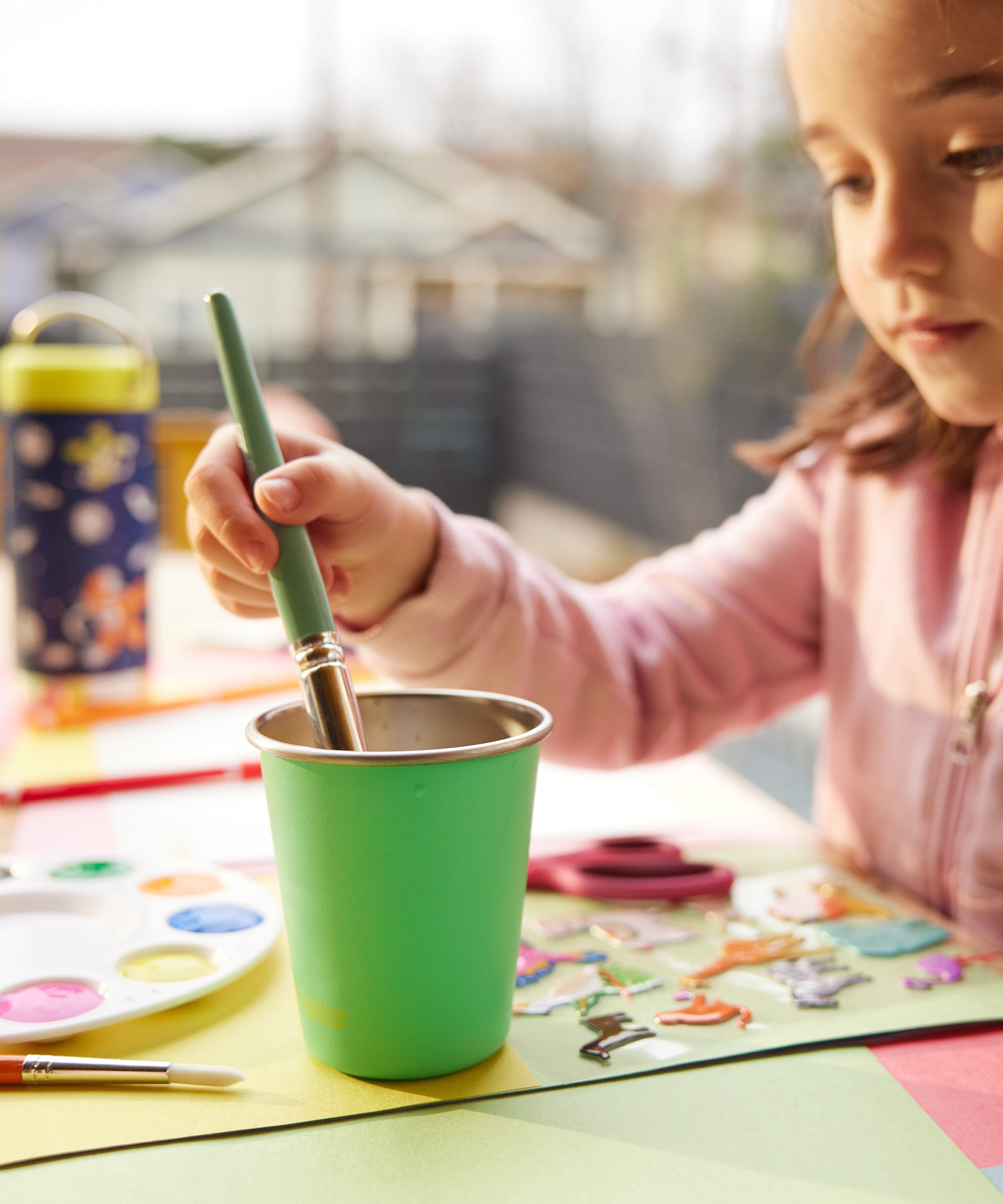 A child using a Klean Kanteen Steel Kid Cup to clean a paint brush. 