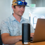 A person sitting at atable in front of a laptop with Klean Kanteen 12oz TKWide Cafe in the black colour placed in front of them.