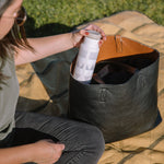 Close up of woman pulling a Klean Kanteen insulated bottle in the salt flats colour out of a black handbag