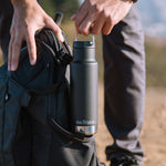 Close up of man putting the Klean Kanteen 12oz eco-friendly metal water bottle in the side pocket of a backpack