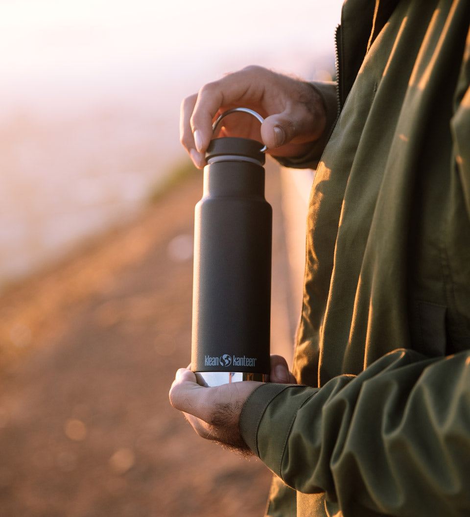 Close up of man holding the Klean Kanteen 12oz insulated drinks bottle at sunset